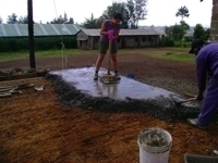 Helping to lay the concrete on the floor Helping to lay the concrete on the floor